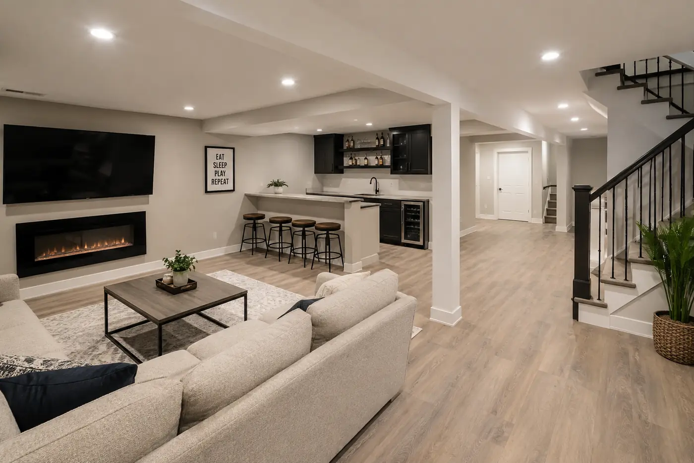 Basement rec room with linear electric fireplace, dark bar cabinets and open staircase in Mason, OH