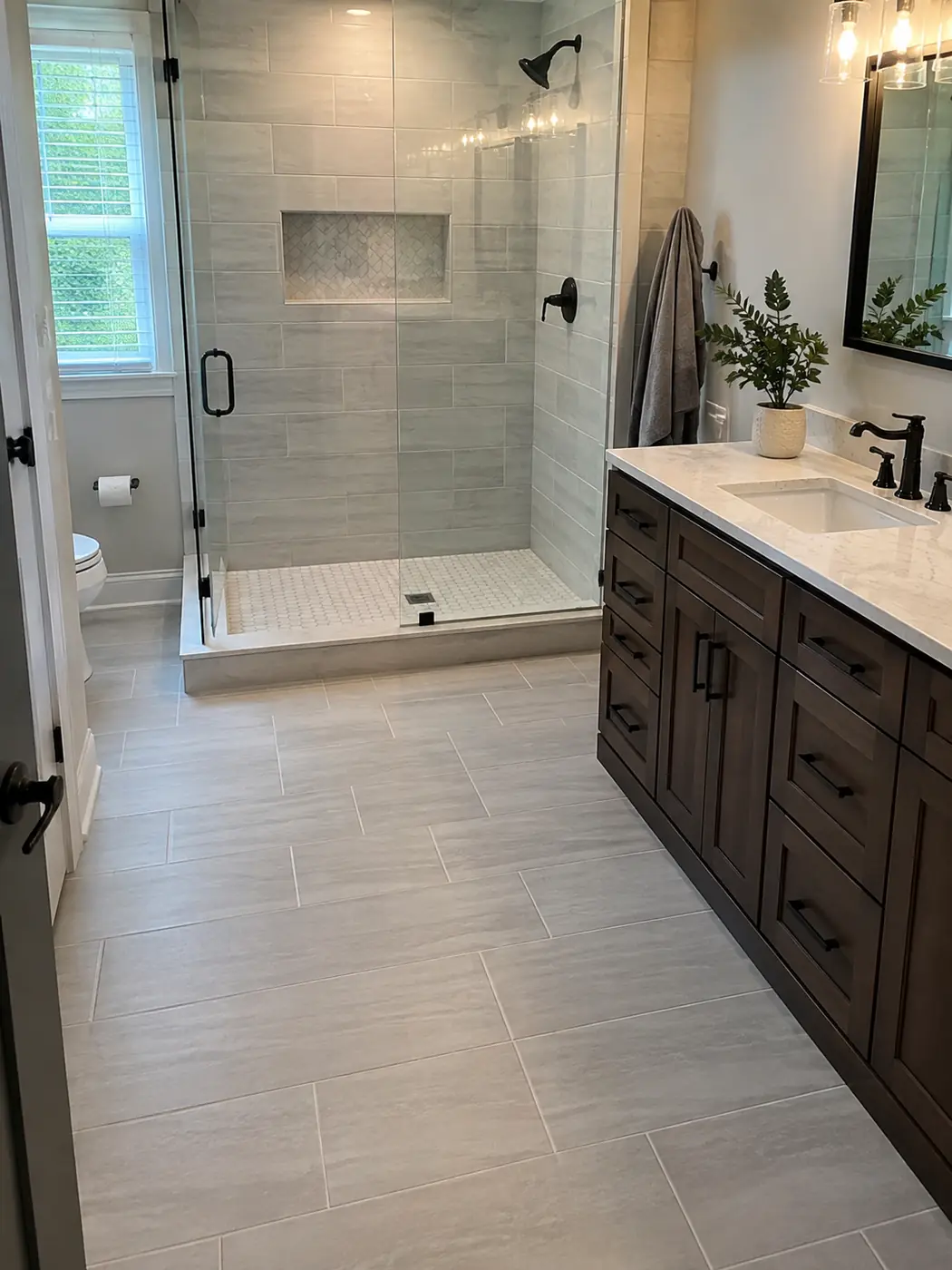 Large-format tile shower with niche, glass door and dark walnut vanity in Mason, OH