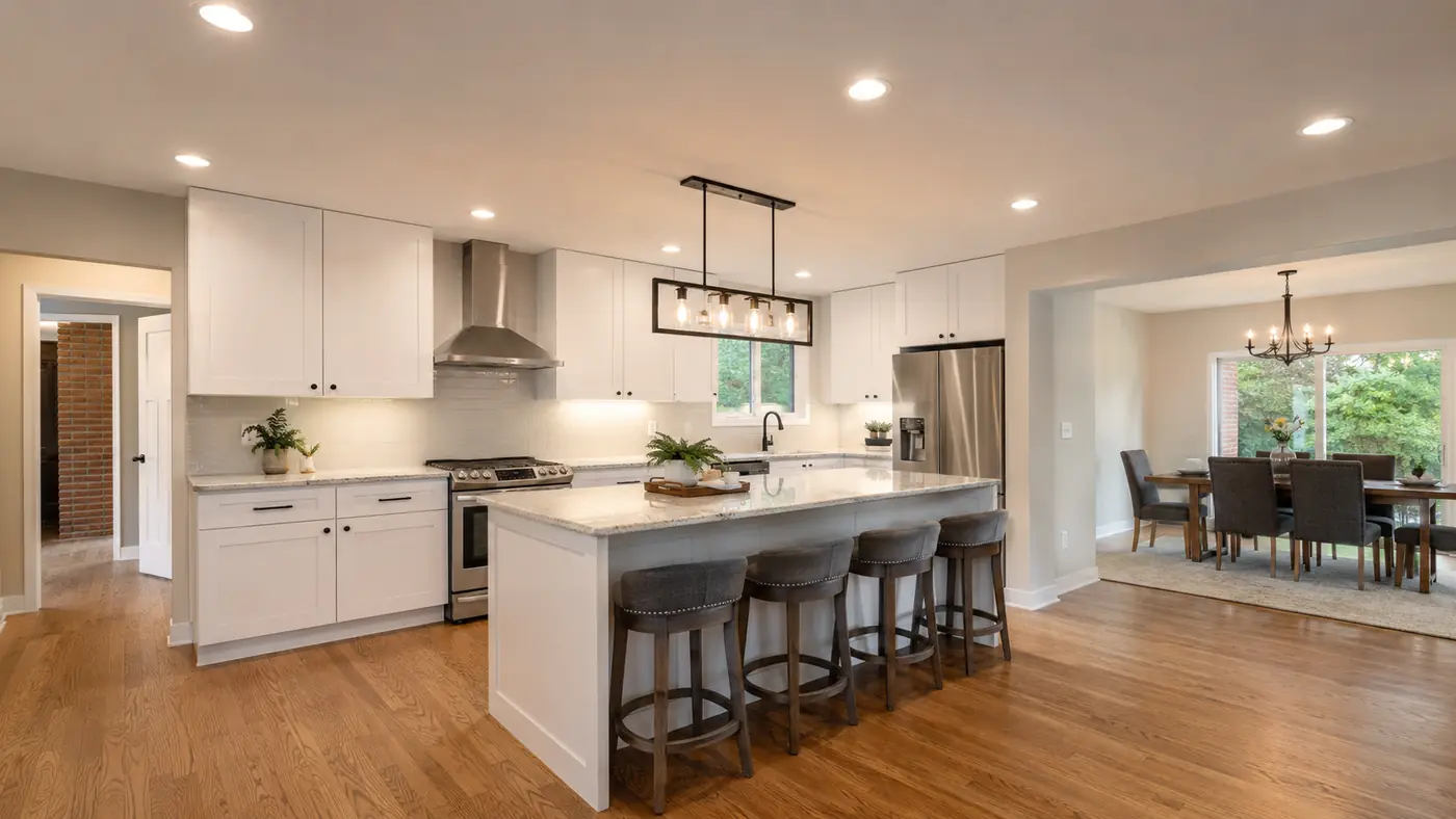 Linear pendant light over a white kitchen island with recessed cans in Mason, OH
