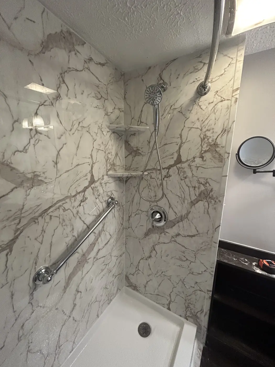 Marble-look shower with grab bars, handheld sprayer and corner shelf in Mason, OH