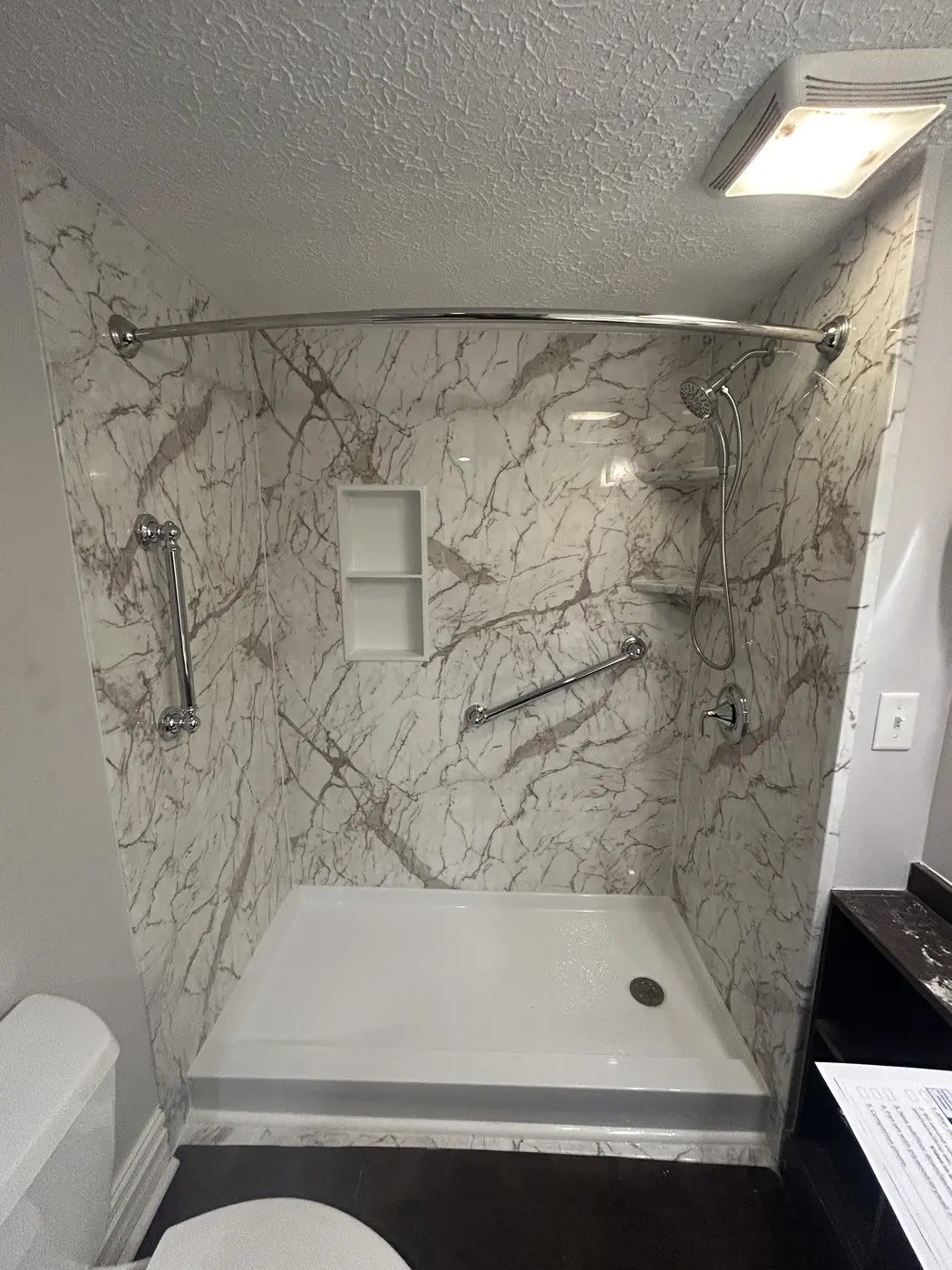 Marble-pattern shower surround with curved curtain rod, niche and grab bars in Mason, OH