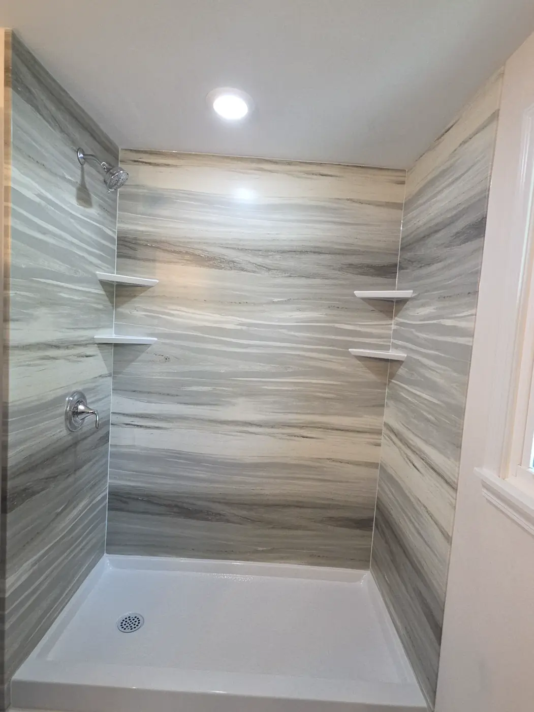 Striated stone-look shower walls with two corner shelves and a white shower base in Mason, OH