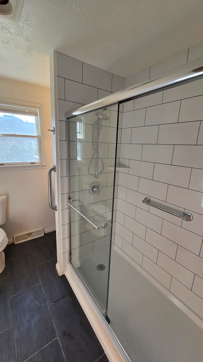 Subway tile shower with sliding glass door, window and slate-look floor tile in Mason, OH
